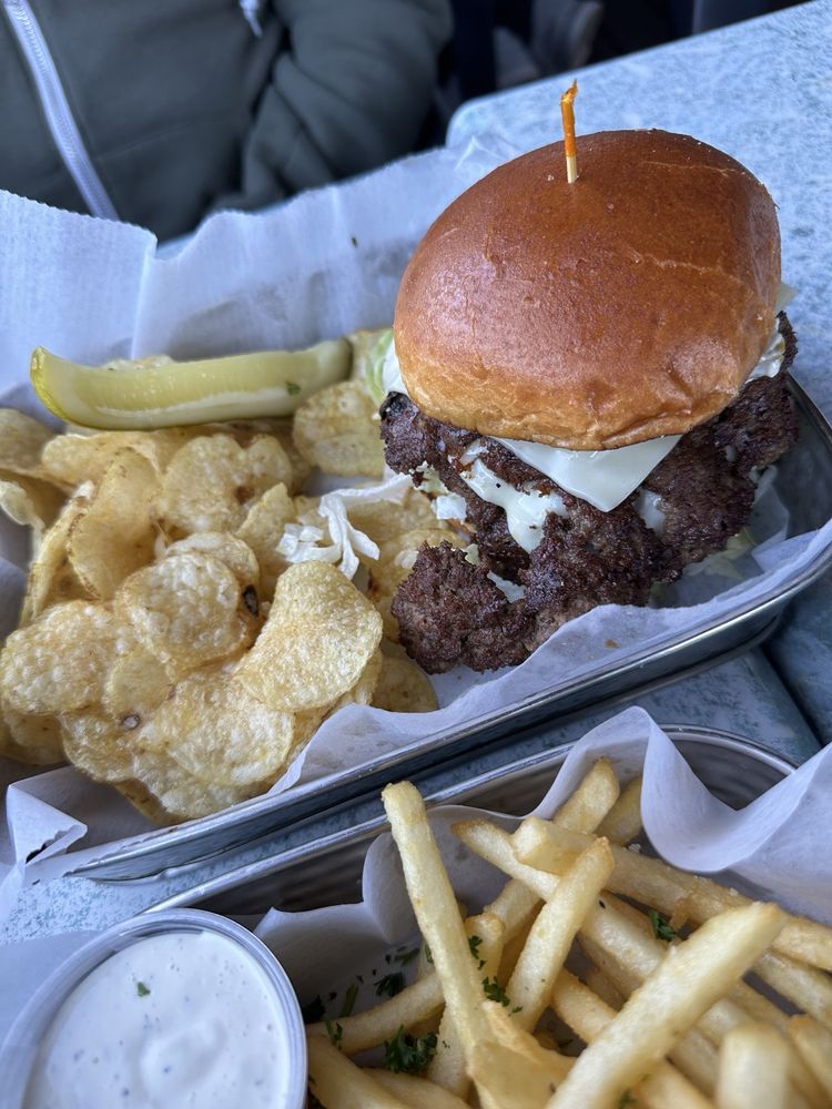Burger on a brioche bun served with kettle chips and fries at Logan's Alley